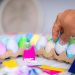 a person is putting colored eggs in a carton