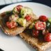 bread with tomato and green vegetable on white ceramic plate
