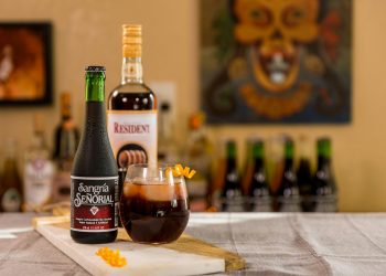 black glass bottle beside clear drinking glass