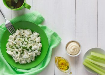 a green bowl filled with food next to a cup of tea