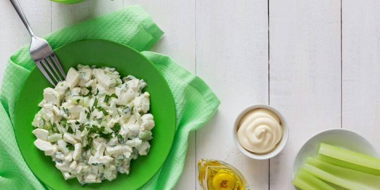 a green bowl filled with food next to a cup of tea