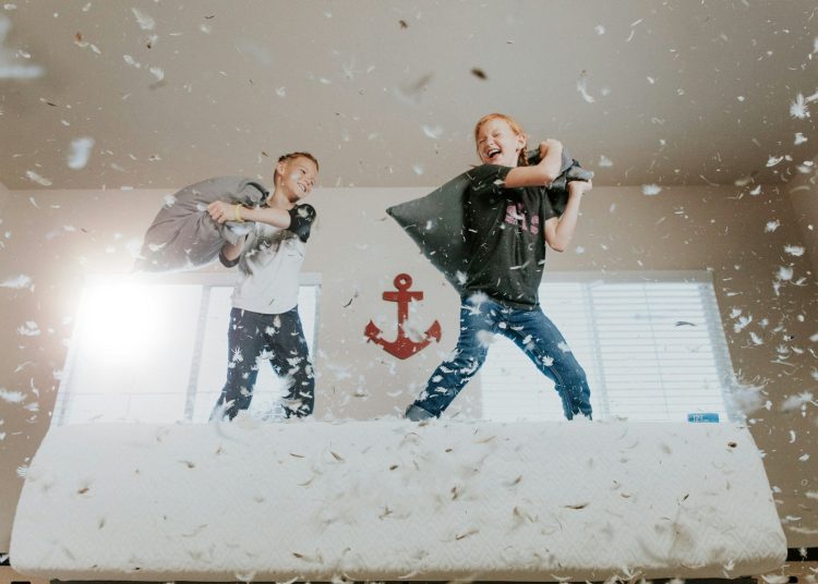 two toddler pillow fighting