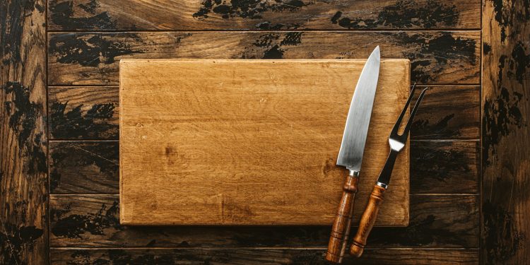 a knife and a board on a wooden surface