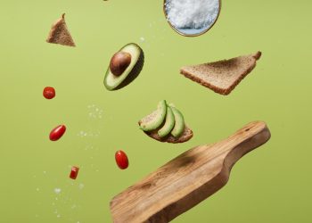 sliced avocado, tomatoes, and bread on a green surface