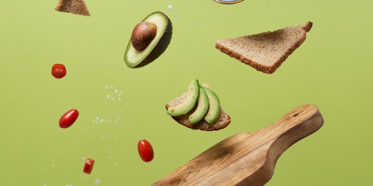 sliced avocado, tomatoes, and bread on a green surface